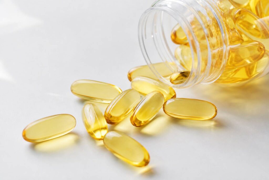 Capsules d'oméga-3 versées sur une surface blanche lumière naturelle